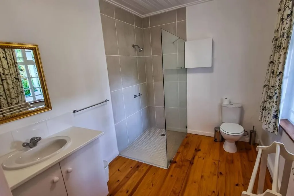 Spacious bathroom with walk-in shower, vanity sink, and wooden flooring