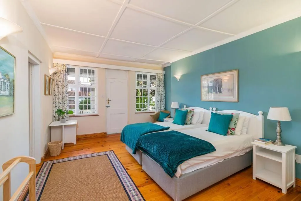 Bright bedroom with turquoise accent wall, queen bed, white nightstands, wooden floors
