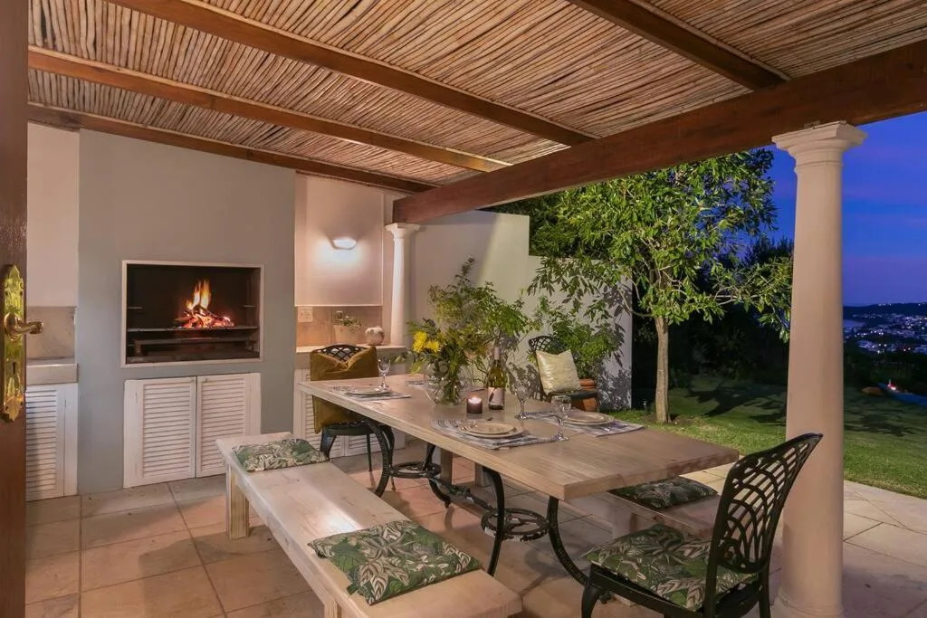 Covered outdoor dining area with fireplace and valley views at dusk