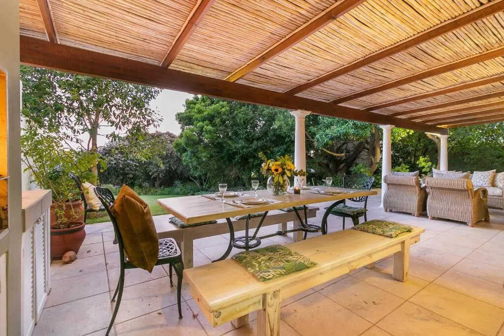 Covered patio with dining table, chairs, and garden views