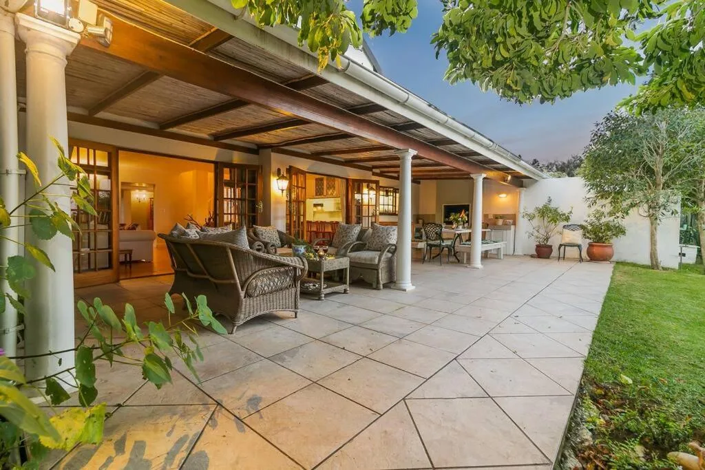 Spacious covered patio with wicker seating and manicured lawn
