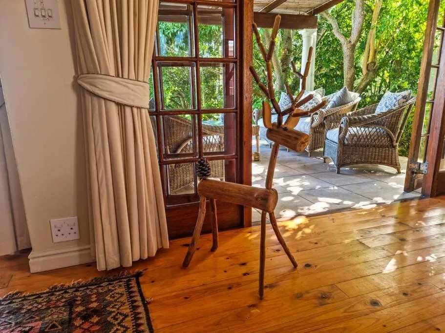 Covered patio with wooden chairs, glass doors, and shaded garden views