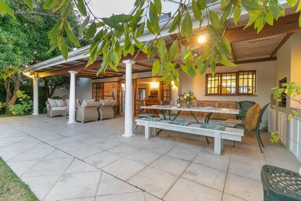 Covered patio with dining table, seating, and lush hanging foliage overhead