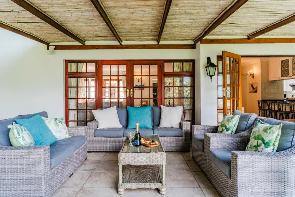 Covered outdoor lounge with wicker seating and ocean views through glass doors
