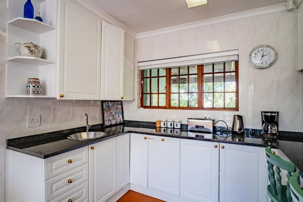 Bright white kitchen with black countertops and wooden window frame