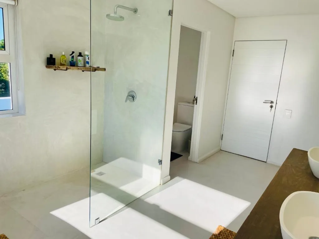 Modern bathroom with walk-in shower, dual vanities, and natural light from window