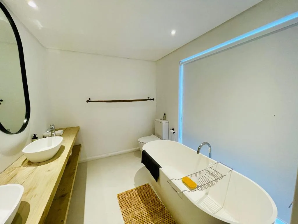 Modern bathroom with freestanding bathtub, wooden vanity, and round sink