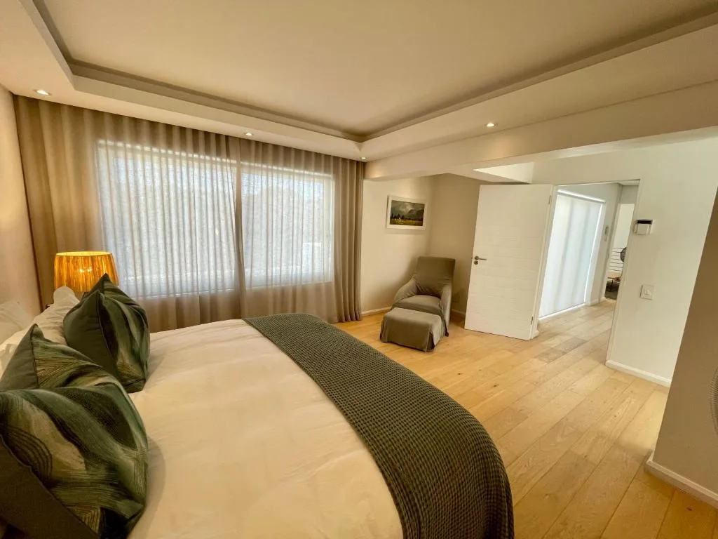 Spacious bedroom with queen bed, armchair, and large windows with curtains