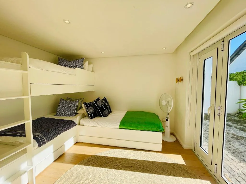 Bright bedroom with bunk beds and single bed, green bedding, wooden flooring