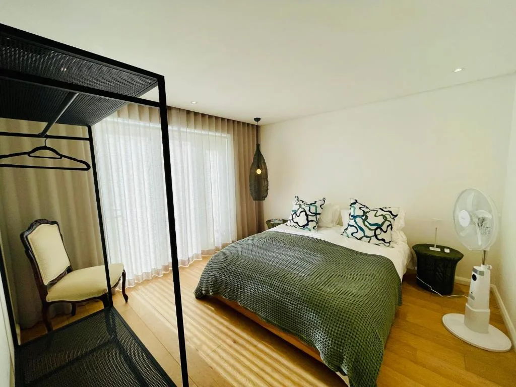 Spacious bedroom with king bed, four-poster frame, and garden views