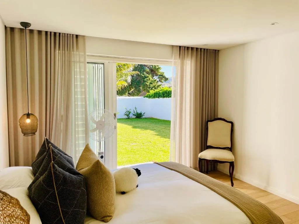 Bright bedroom with bed, garden view through glass doors, elegant furnishings