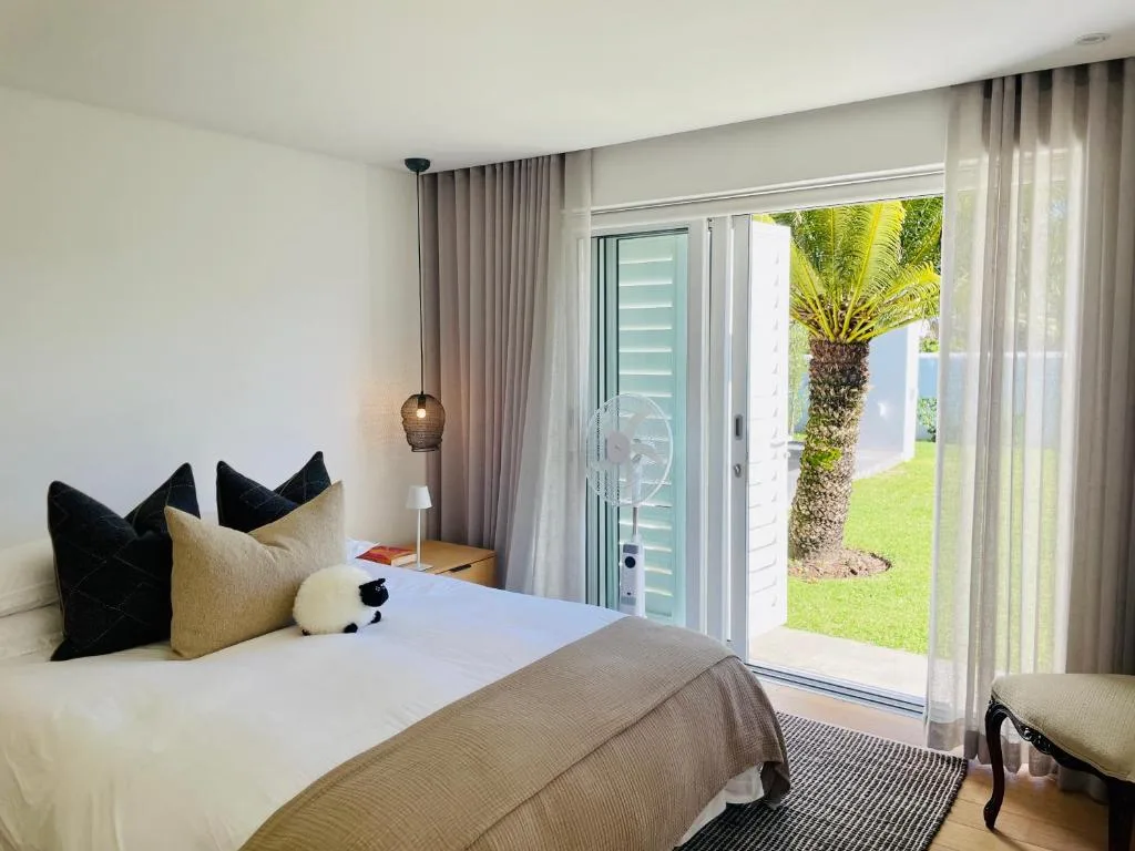 Bright bedroom with bed, black pillows, pendant light, garden view doors