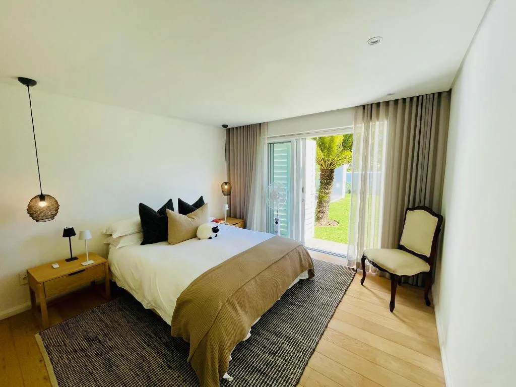 Modern bedroom with bed, garden view through sliding doors and contemporary lighting