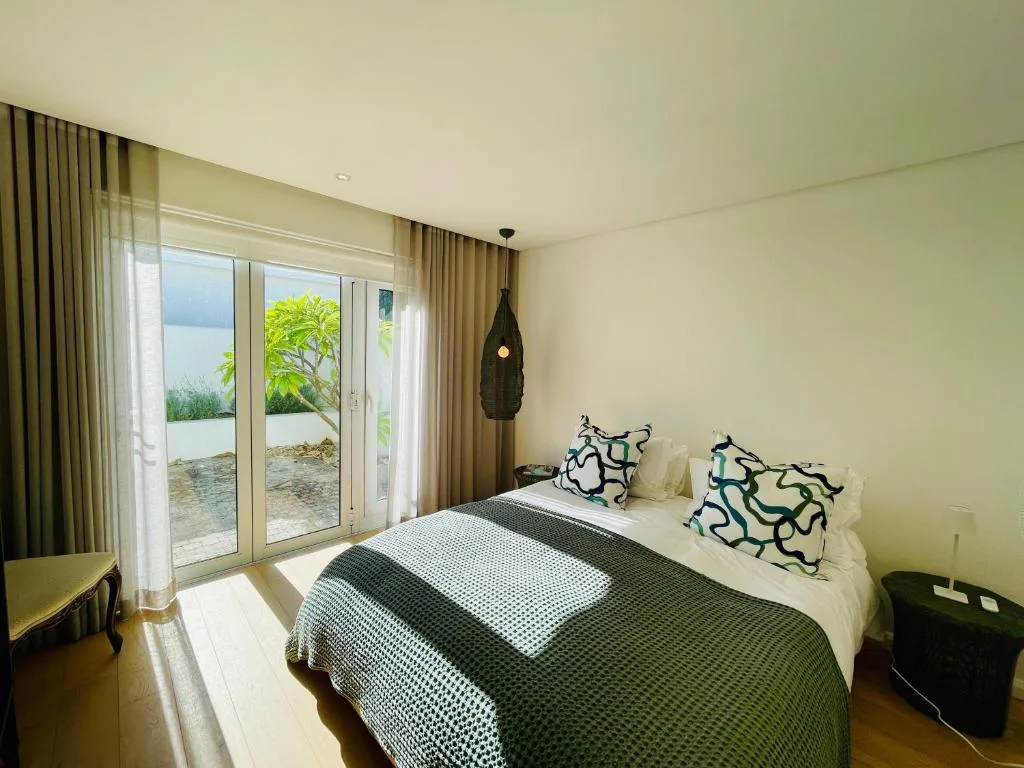 Spacious bedroom with ocean view through sliding glass doors and patio access