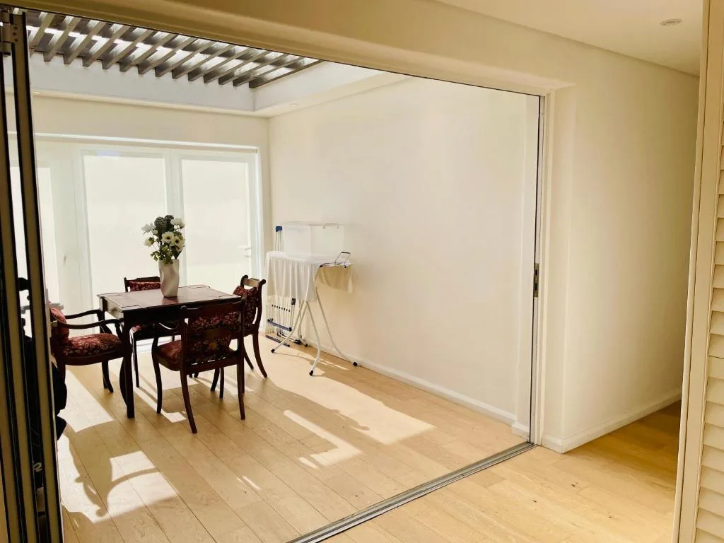 Bright indoor-outdoor dining area with wooden table and sliding glass doors