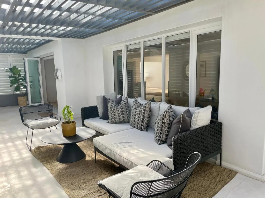 Modern covered patio with lounge seating, chairs, and potted plants