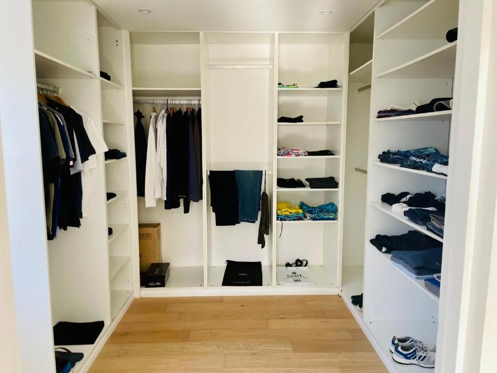 Walk-in closet with white built-in shelving and hanging rails for storage