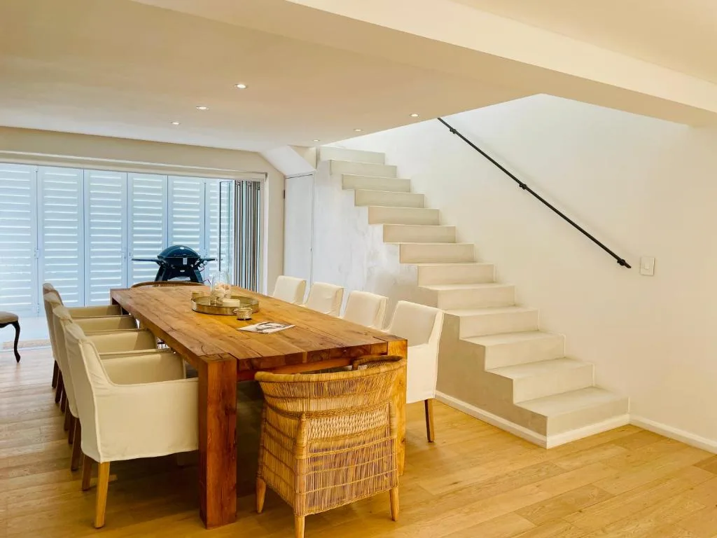 Wooden dining table with cream chairs and wicker seating in open-plan space
