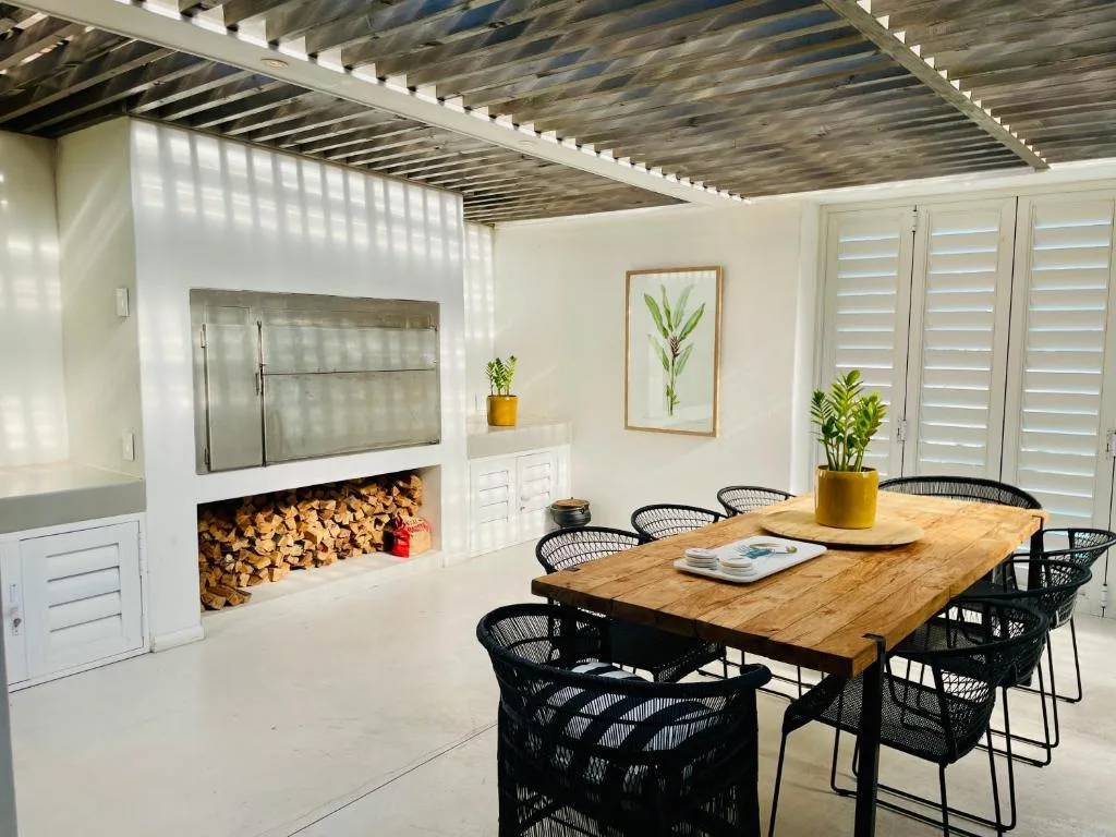 Modern dining area with wooden table and black chairs, fireplace backdrop