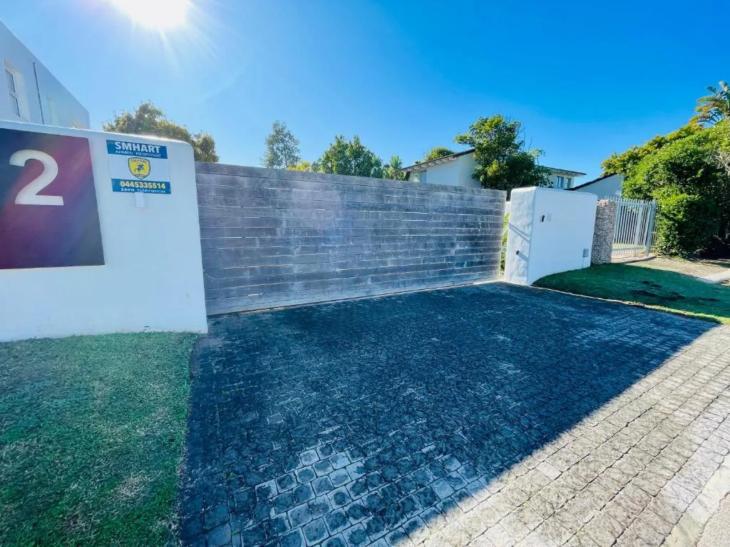 Driveway and entrance gate with modern paving and landscaping
