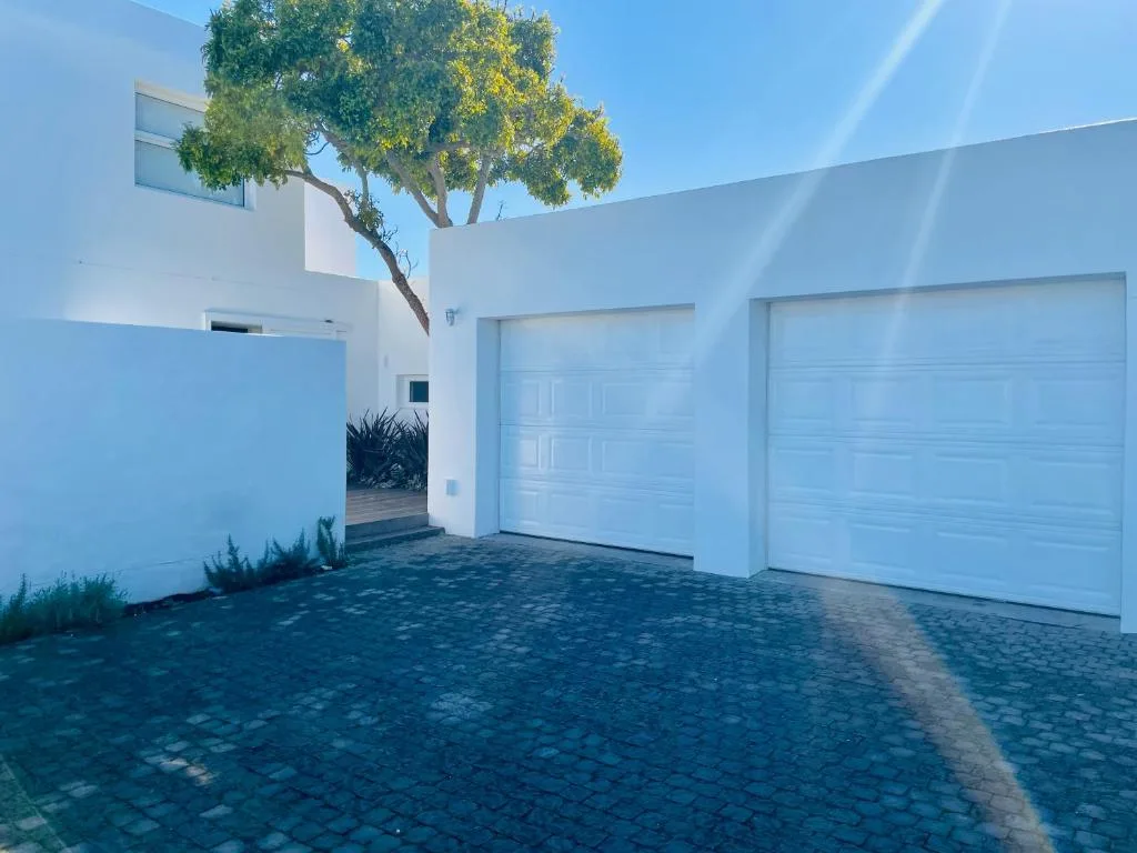 Modern white villa exterior with double garage and mature tree