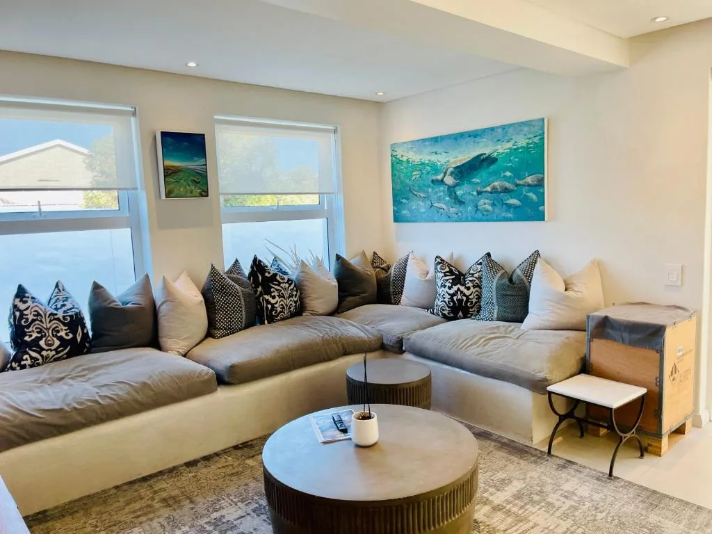 Modern lounge with cream sectional sofa, patterned cushions, and ocean artwork