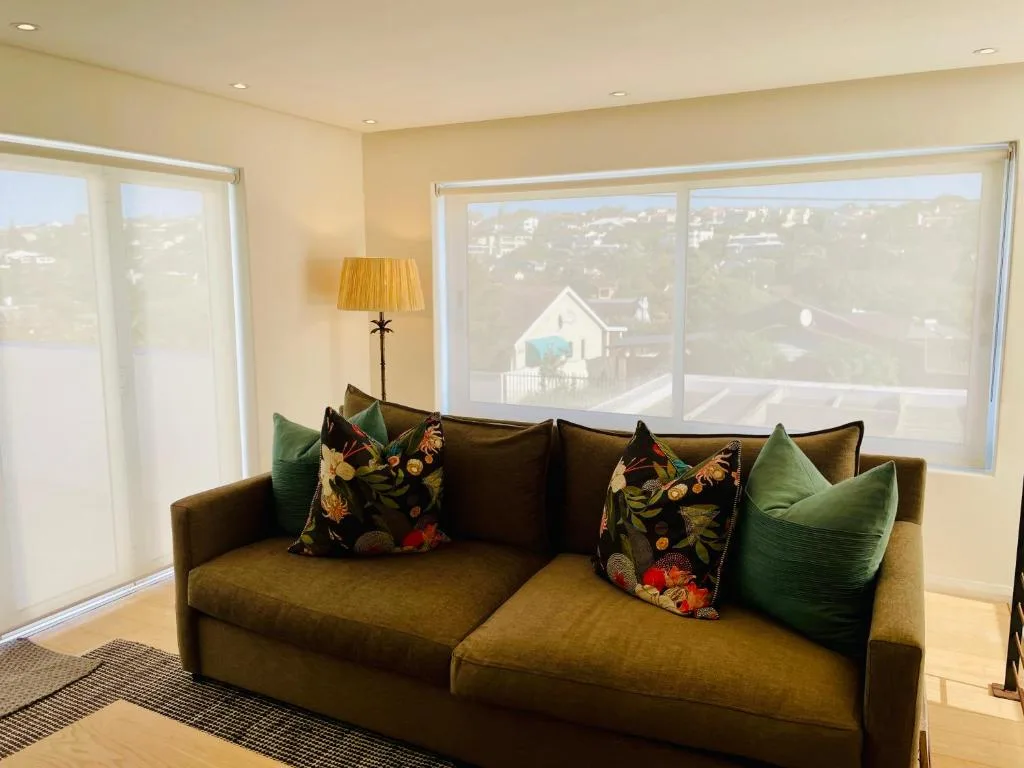 Comfortable mustard sofa with colorful cushions overlooking coastal landscape