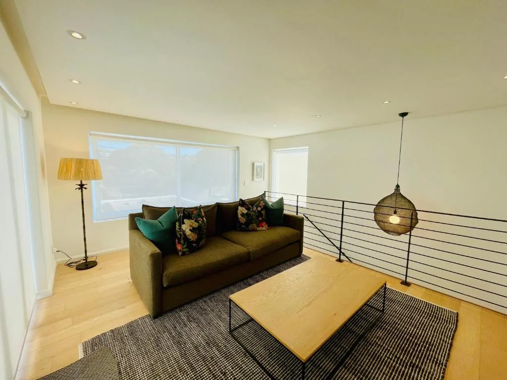 Modern lounge with olive sofa, wooden coffee table, and ocean views through large windows