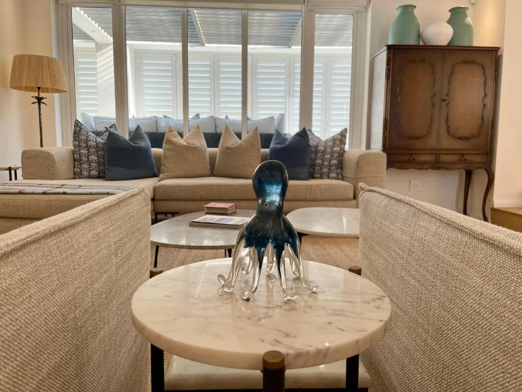 Spacious lounge with neutral sofas, marble coffee table, and shuttered windows