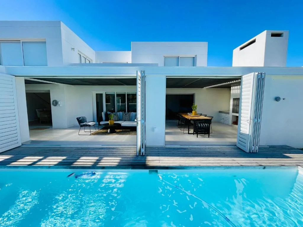 Sparkling blue pool with modern white villa and open deck areas