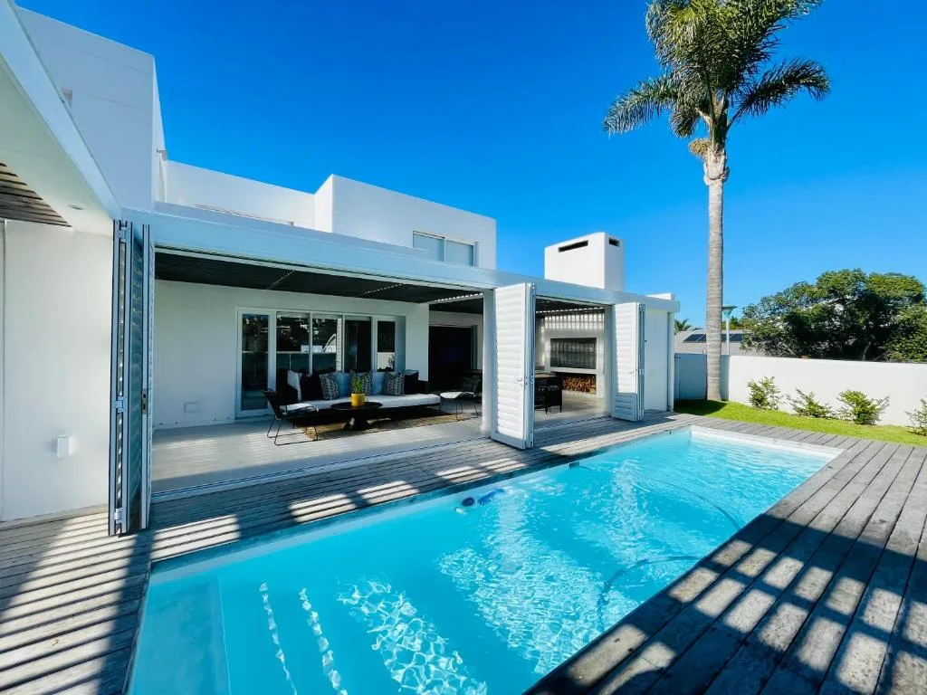 Sparkling swimming pool with modern white villa and wooden deck