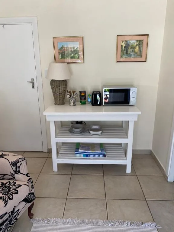 White kitchen counter with microwave, lamp, and storage shelves