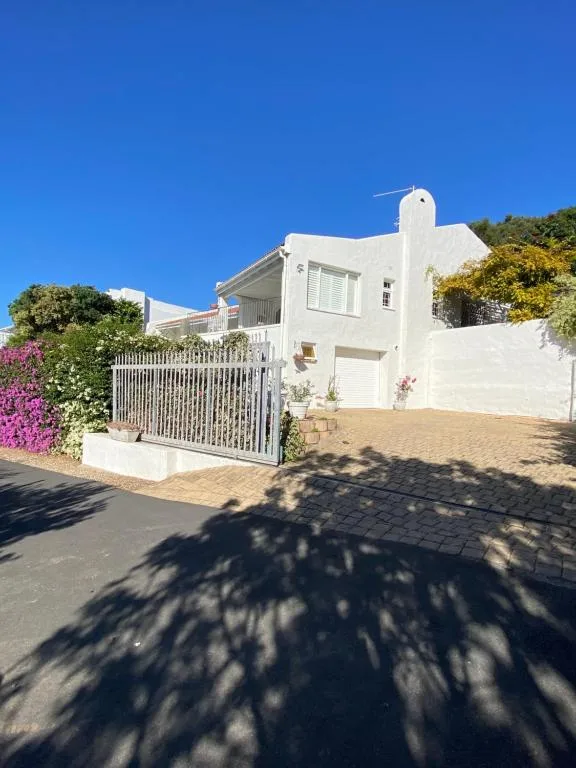 White modern cottage with gated driveway and flowering magenta bougainvillea