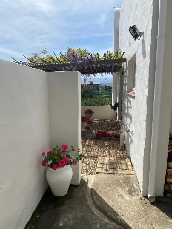 White-walled garden pathway with flowering plants and countryside views beyond