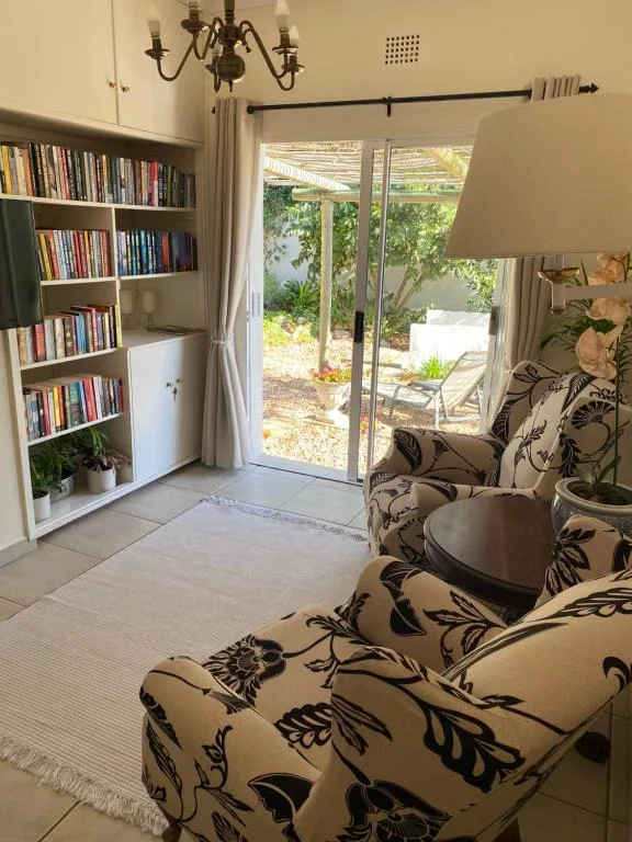 Bright lounge with patterned armchair, bookshelf, and garden views through sliding doors