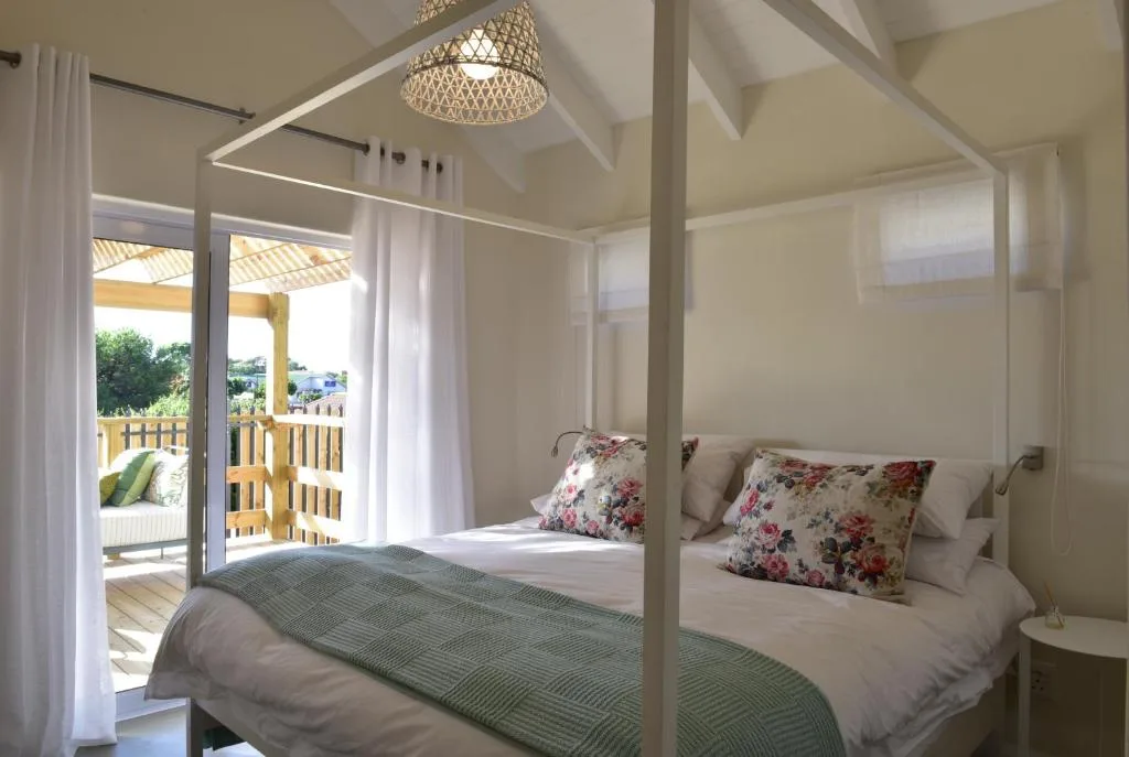 Bright bedroom with four-poster bed and direct deck access via glass doors