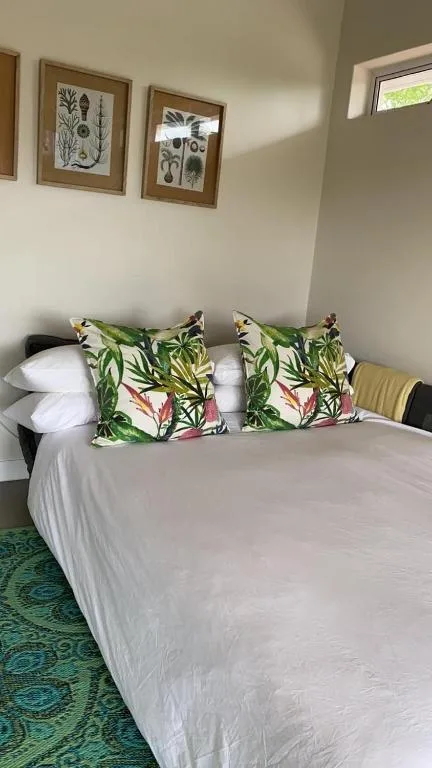 Bright bedroom with white bed, tropical leaf pillows, botanical wall art