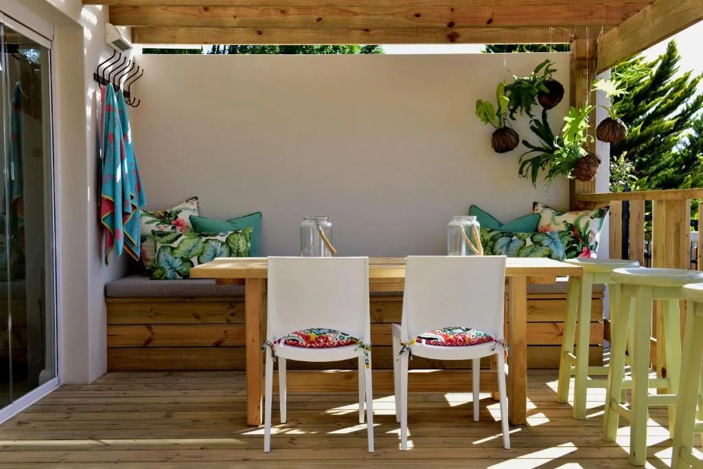 Wooden deck with built-in seating, dining chairs, hanging plants, and garden views