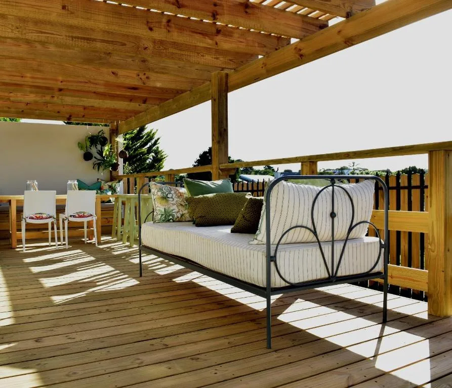 Covered wooden deck with daybed, lounge seating, and garden views