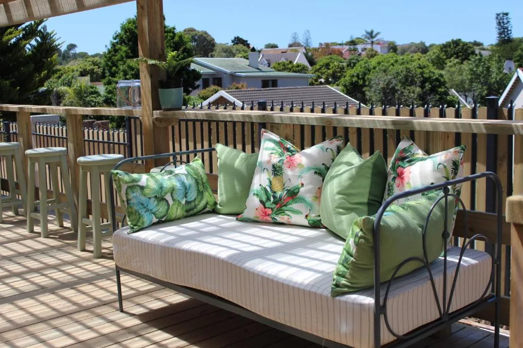 Wooden deck with daybed, colorful cushions, and neighborhood view