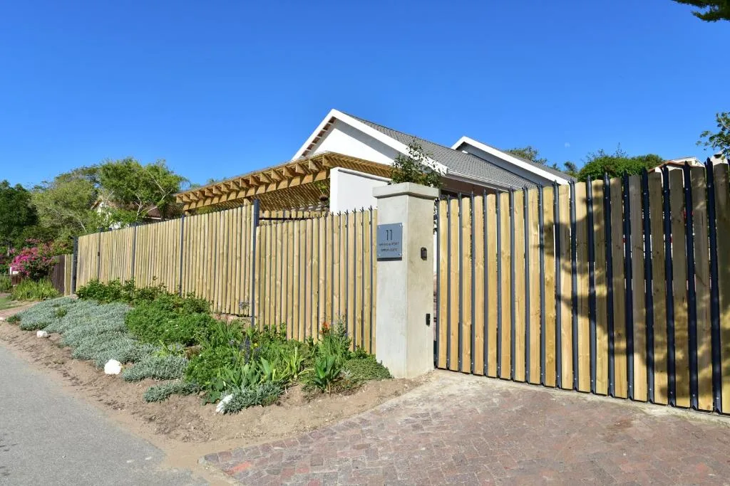 Modern white cottage with timber pergola and black striped gate entrance