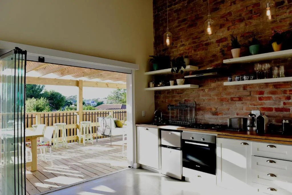 Modern kitchen with white cabinetry, exposed brick wall, and garden view doors