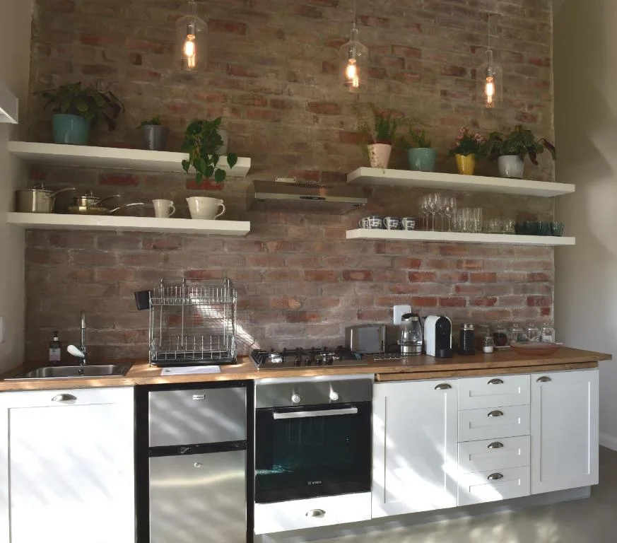 Modern kitchen with exposed brick, white cabinetry, wooden countertops, pendant lighting