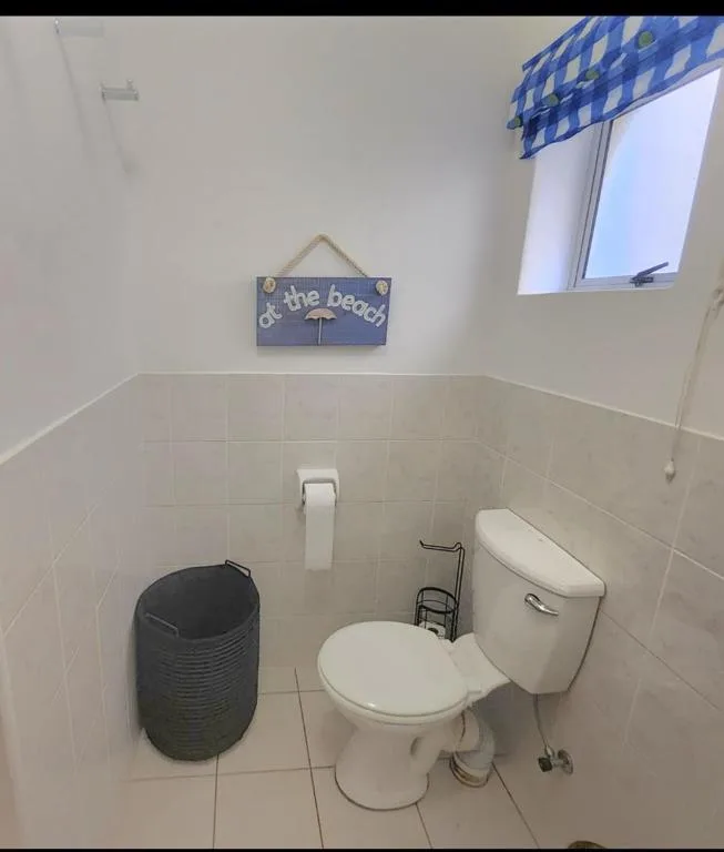 Clean bathroom with toilet, basin, and beach-themed wall decor