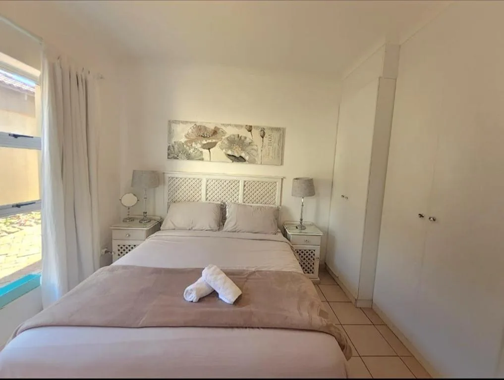 Bright bedroom with double bed, white headboard, and rolled white towels