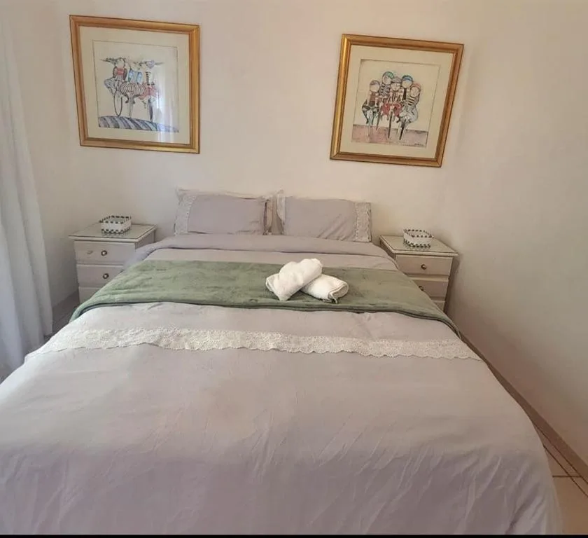 Neat bedroom with double bed, bedside tables, and framed artwork