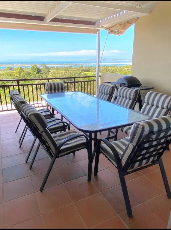 Outdoor dining deck with striped chairs and blue table overlooking lagoon