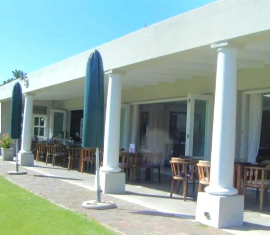 Modern covered patio with wooden chairs and blue umbrellas overlooking lawn