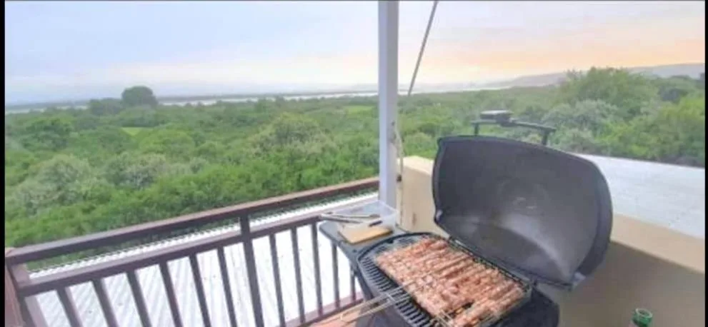 Braai grill on elevated deck overlooking lush green valley landscape