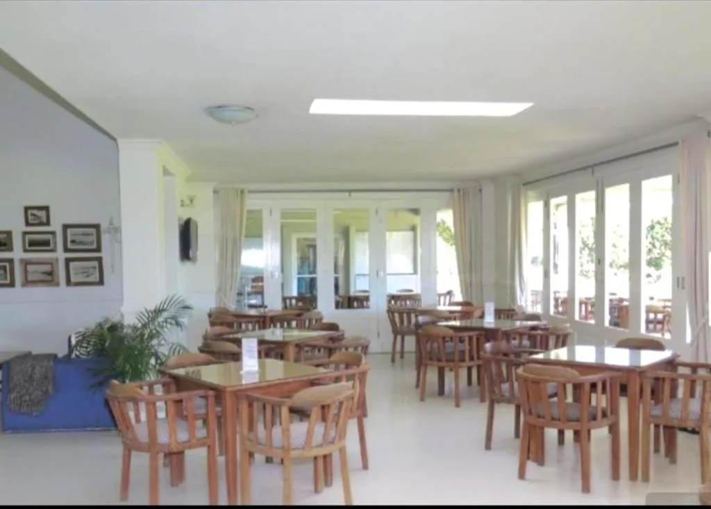 Bright dining area with multiple wooden tables and chairs, large glass doors